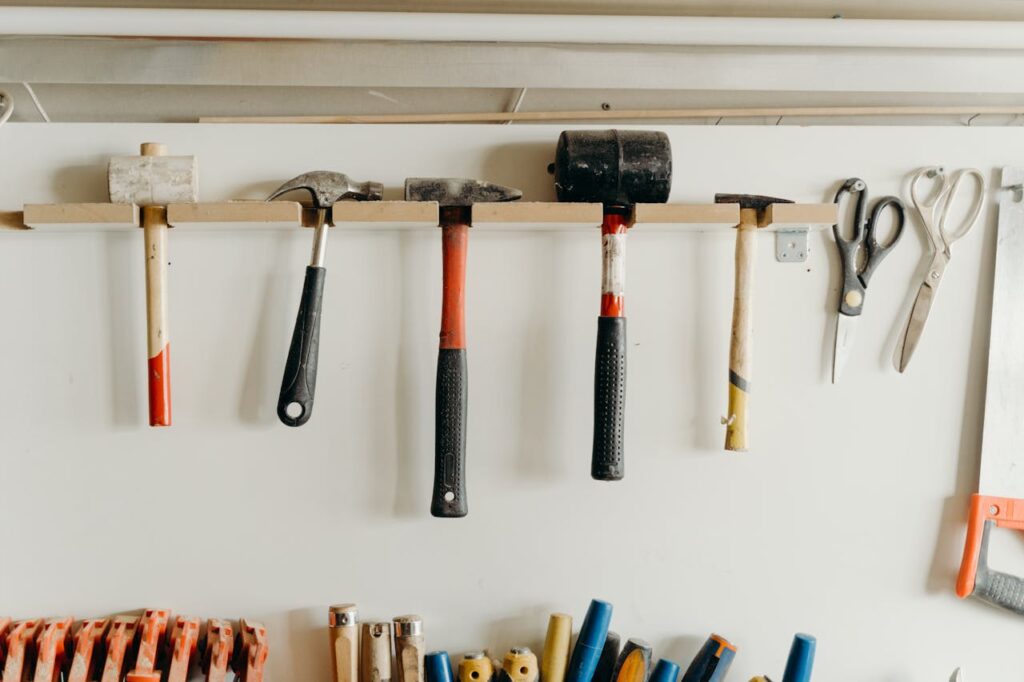 Neatly organized tools hanging on a workshop wall, including hammers and scissors.