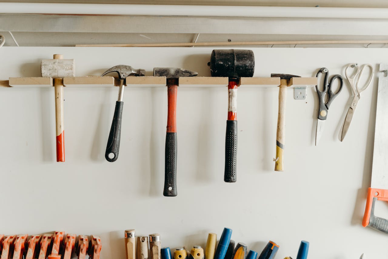 Neatly organized tools hanging on a workshop wall, including hammers and scissors.