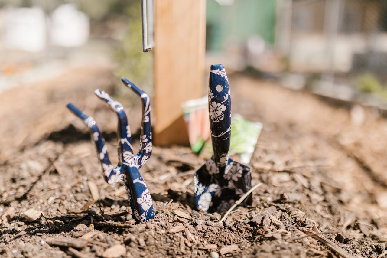 A vibrant close-up of floral-patterned gardening tools in fresh soil, capturing the essence of gardening.